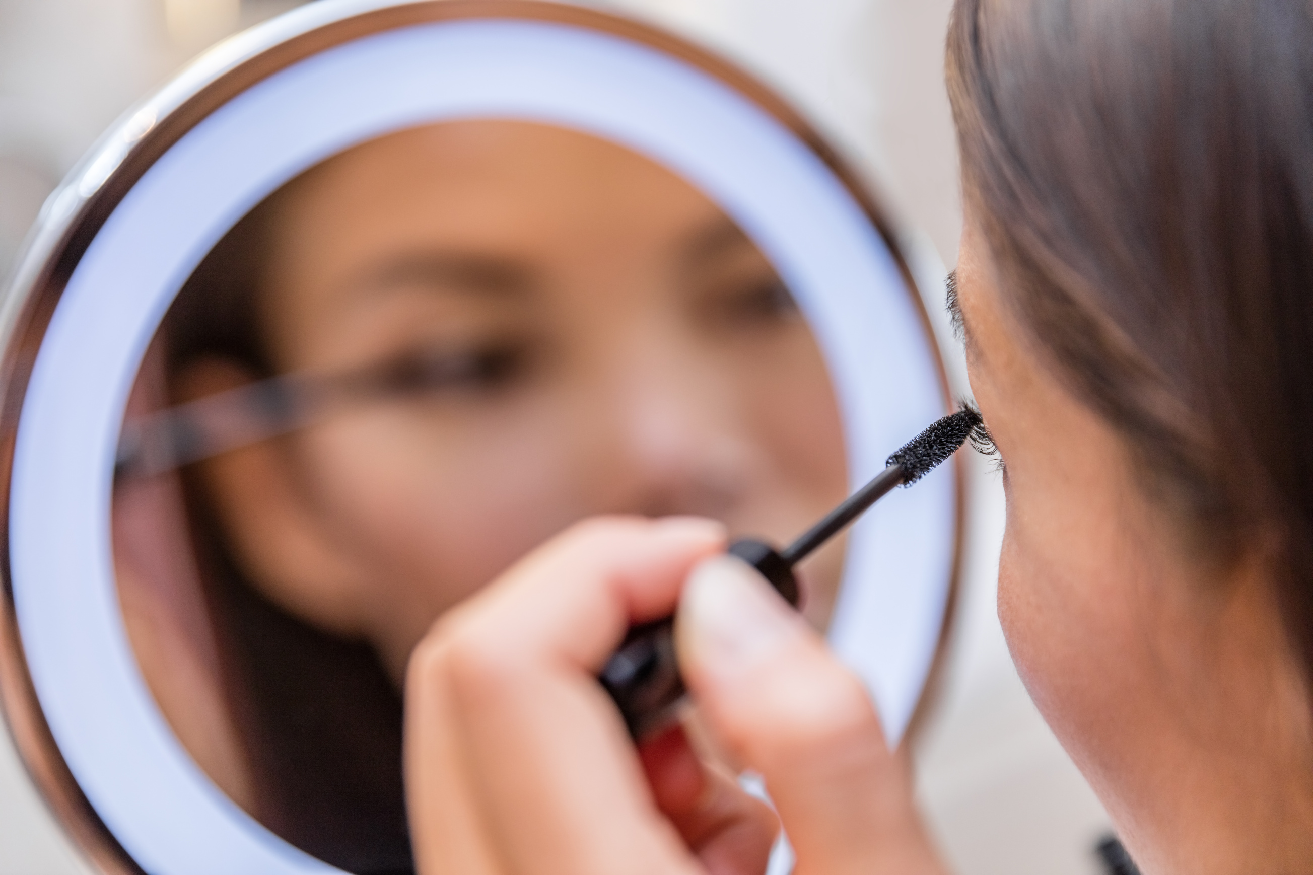 Woman Putting Mascara in Lighted Makeup Mirror